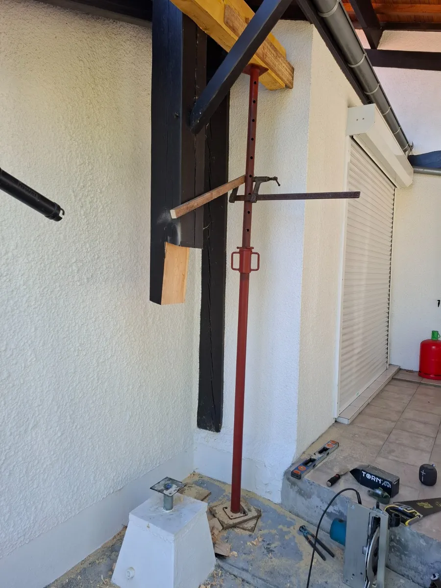 Poteau en bois maintenu par un étai pendant le remplacement de sa partie basse