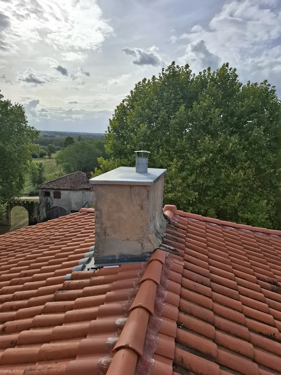 Cheminée coiffée d'un chapeau sur une toiture en tuiles à Betbezer-d'Armagnac