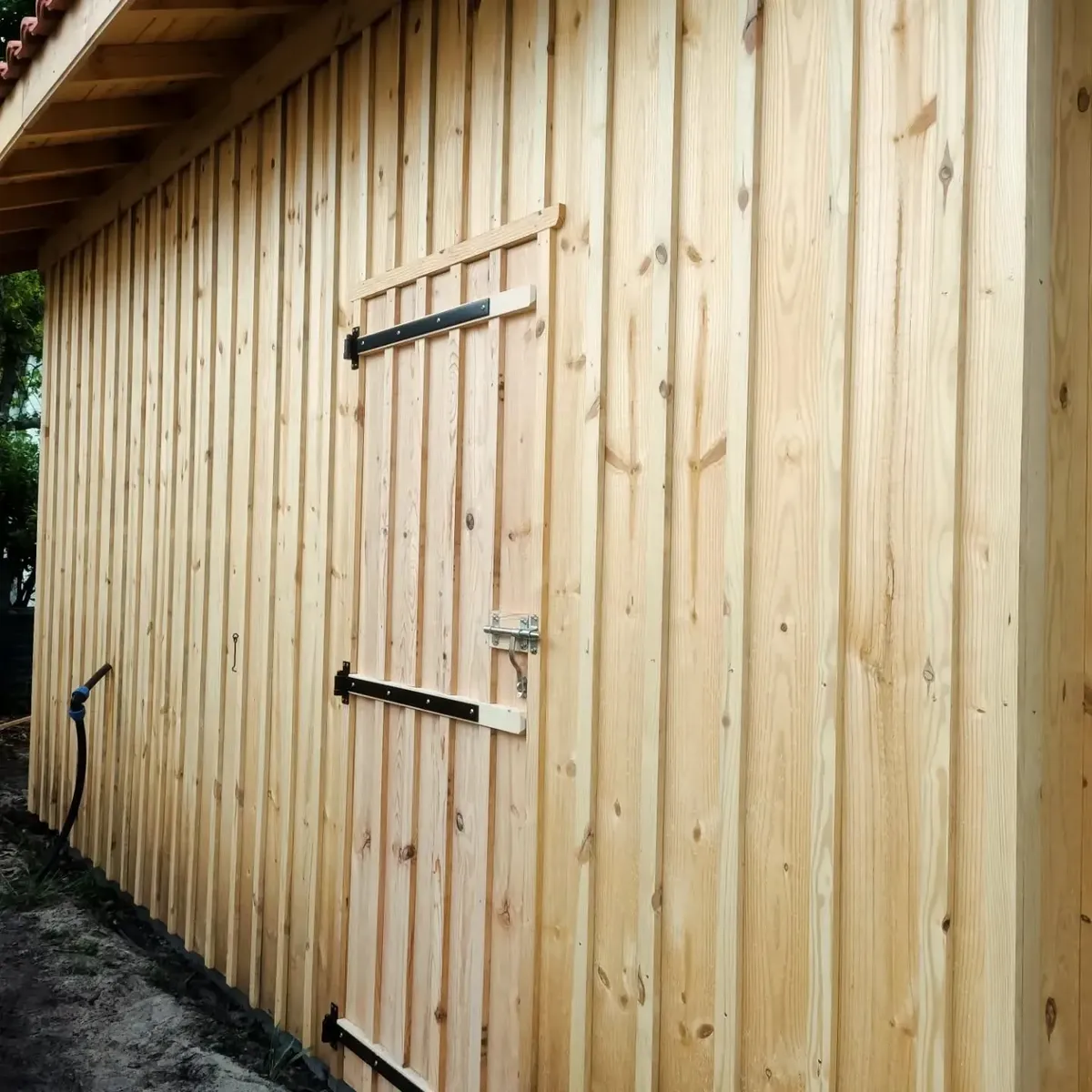 Ossature bois habillée d'un bardage en bois vertical, avec sa porte